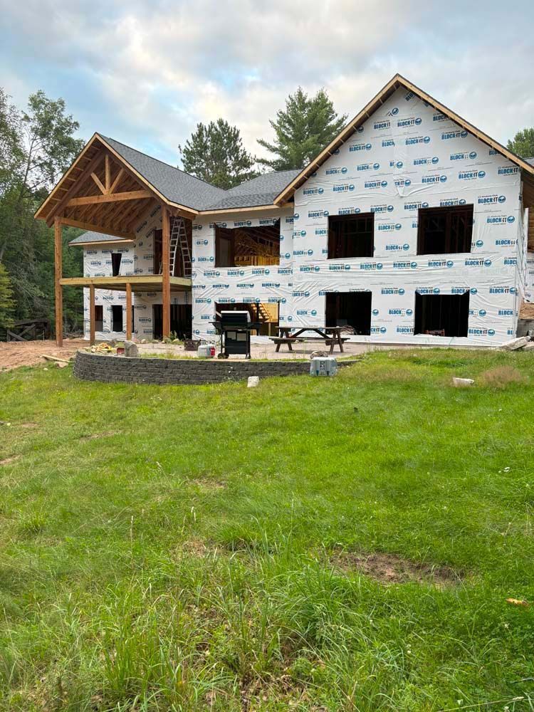 A large house is being built in the middle of a lush green field.