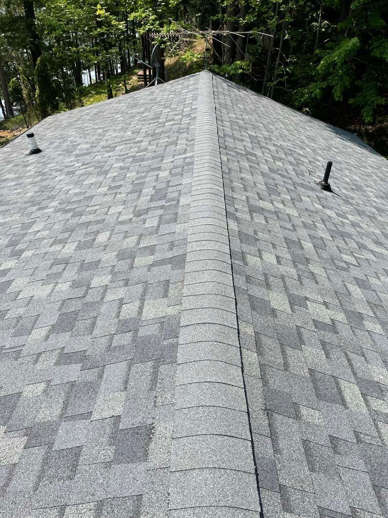 A roof with a lot of shingles on it is surrounded by trees
