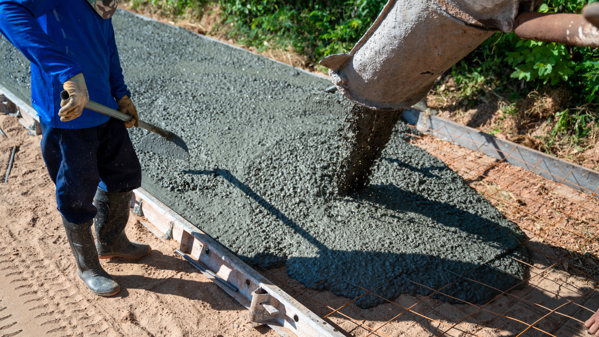 A man is pouring concrete on a sidewalk.