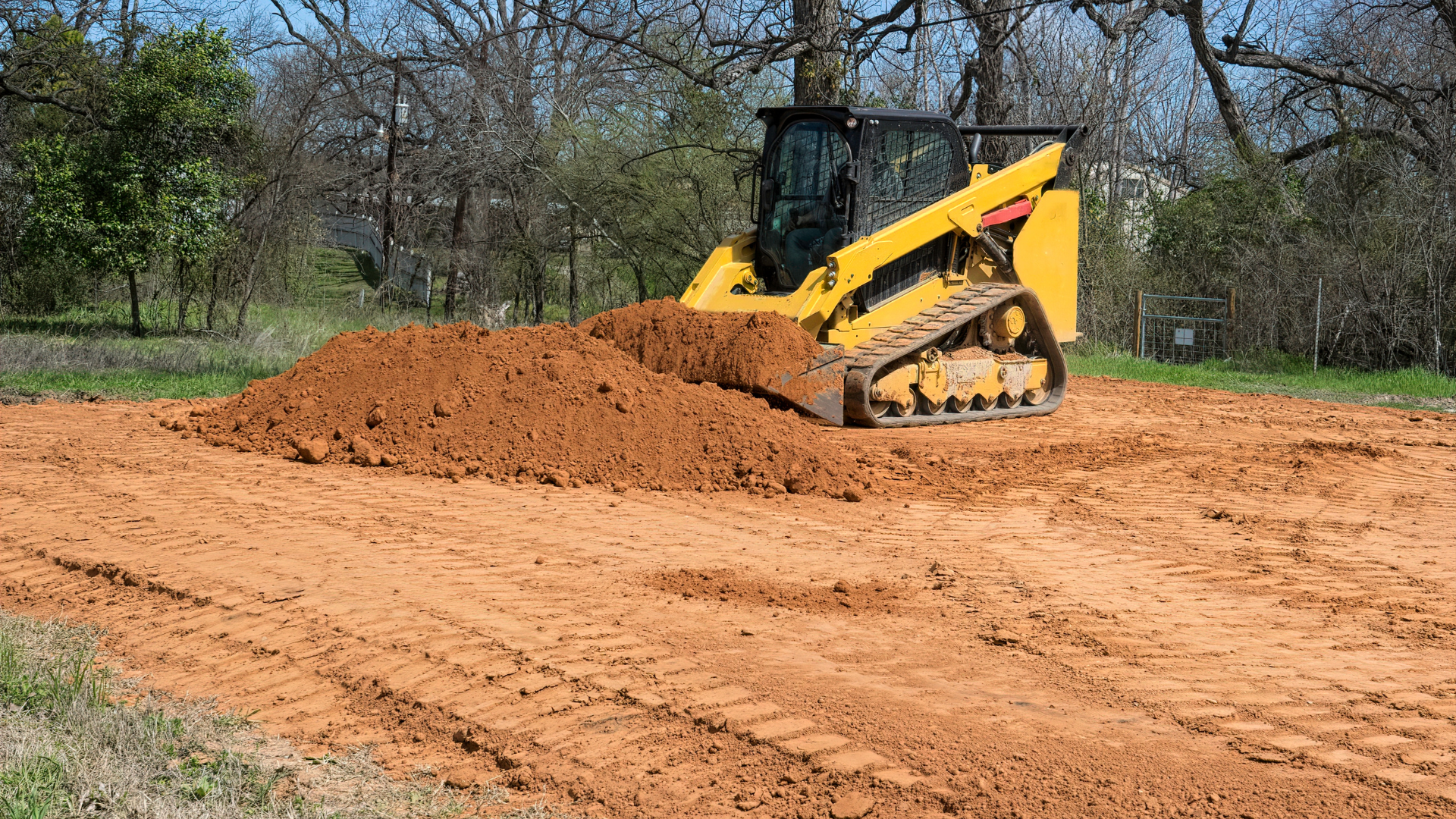 A yellow bulldozer is moving dirt on a dirt road.