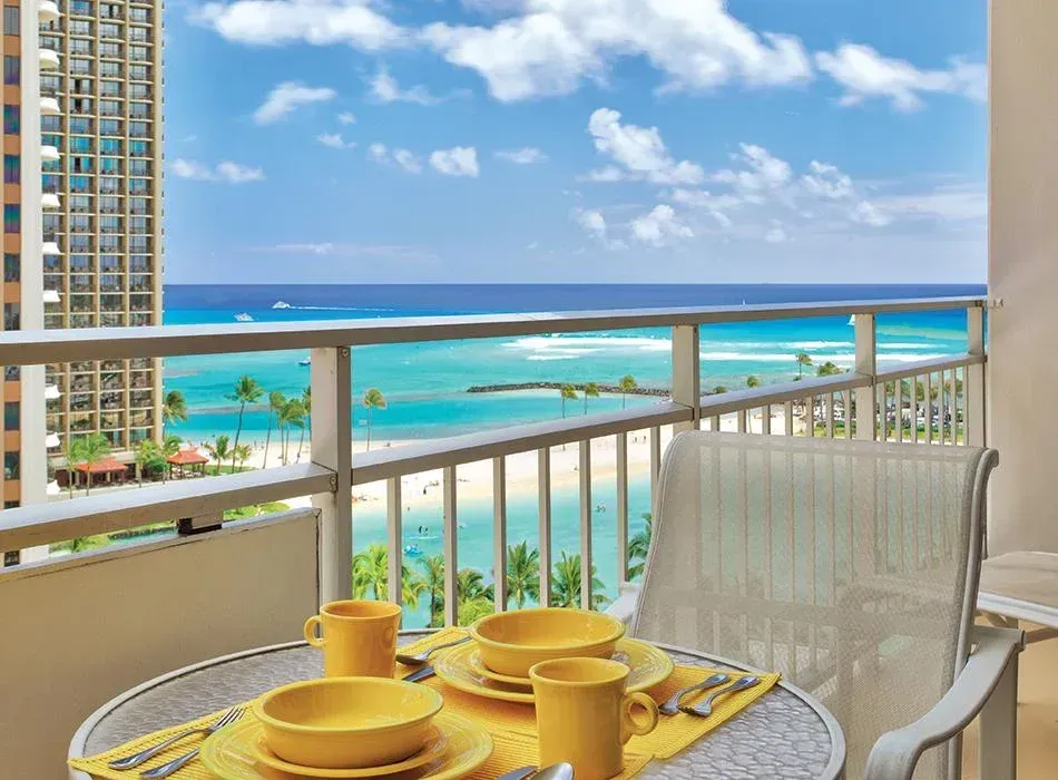 a balcony with a table and chairs and a view of the ocean