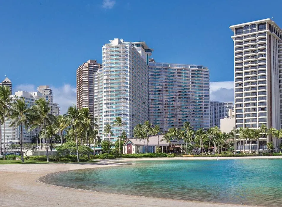 a beach with palm trees and buildings in the background