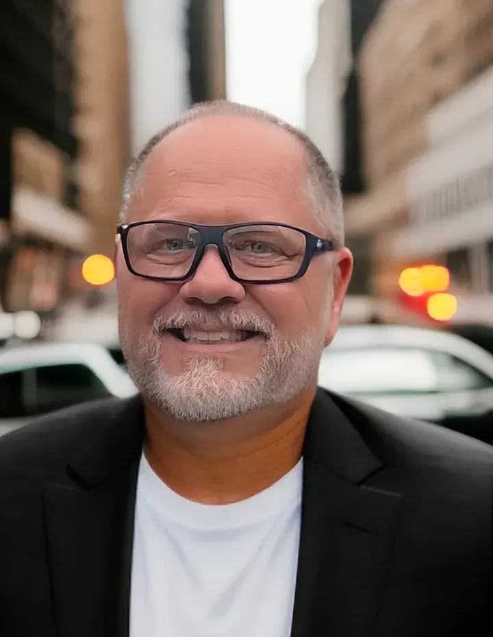 A man with glasses and a beard is smiling for the camera