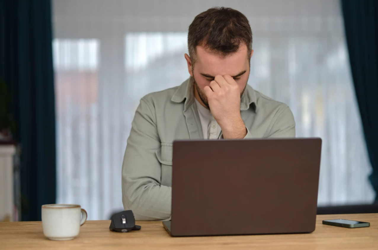 A man is sitting at a desk using a laptop computer.