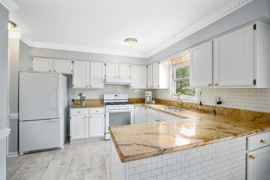 A kitchen with white cabinets and granite counter tops.