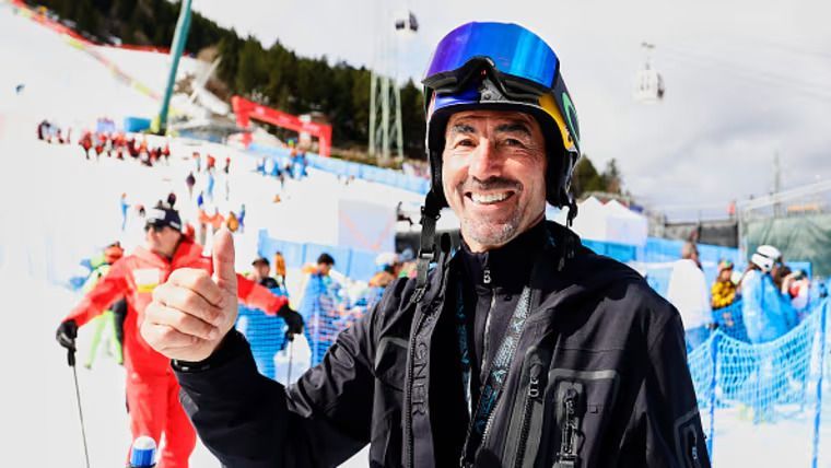 A man wearing a helmet and goggles is giving a thumbs up in the snow.