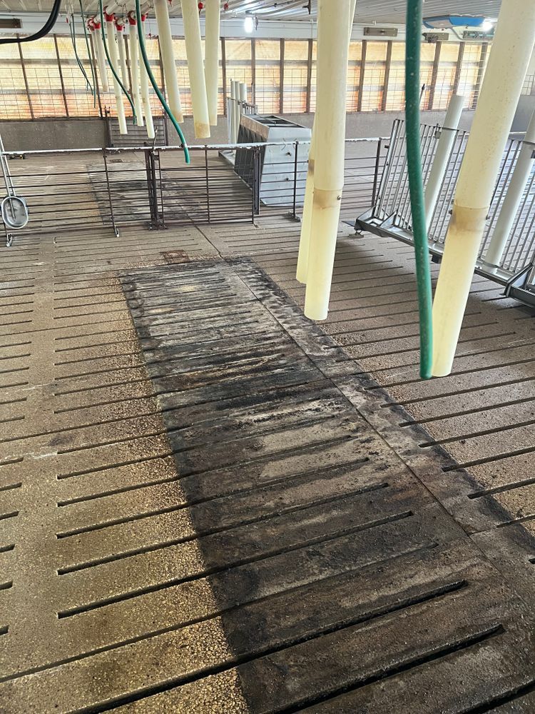 A dirty floor in a building with a hose hanging from the ceiling.