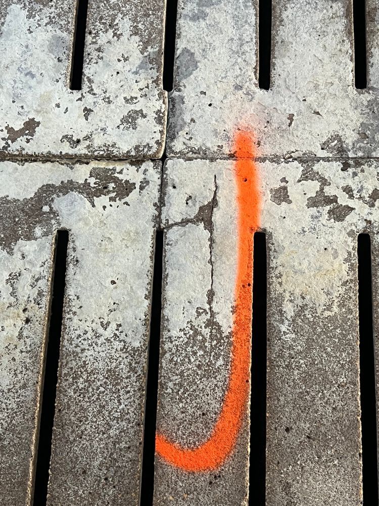 The letter j is painted in orange on a concrete surface
