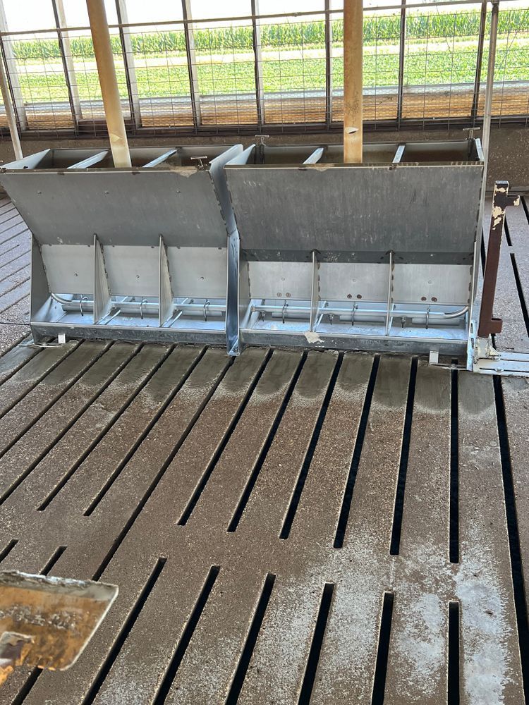 A couple of feeders sitting on top of a dirt floor.