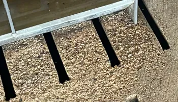 A close up of a fence with shadows on the ground.