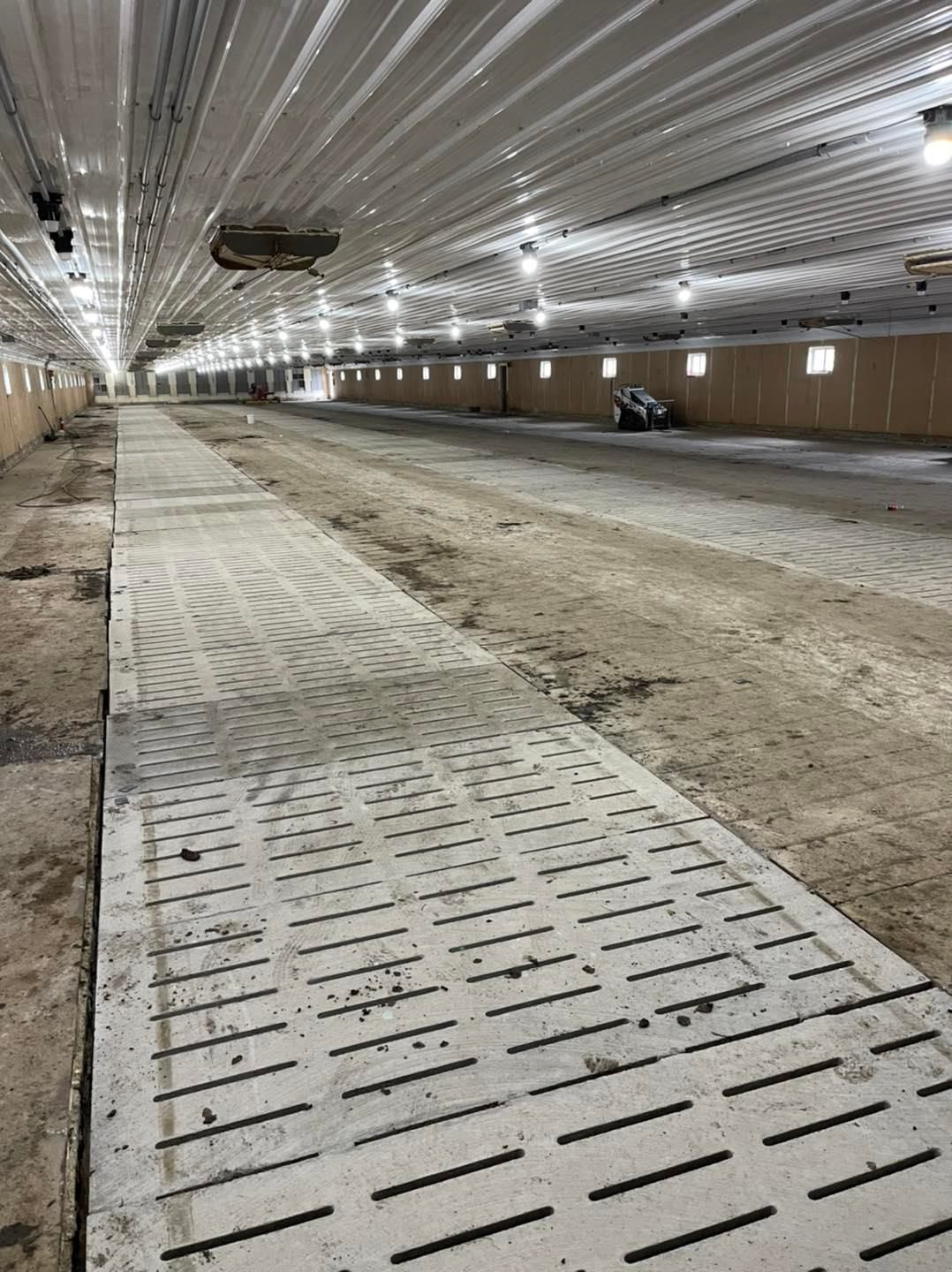 There is a concrete walkway in the middle of a barn.