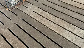 A close up of a wooden deck with a broom on it.