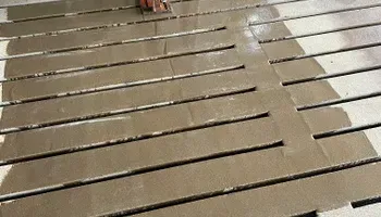 A person is painting a wooden floor with a brush.