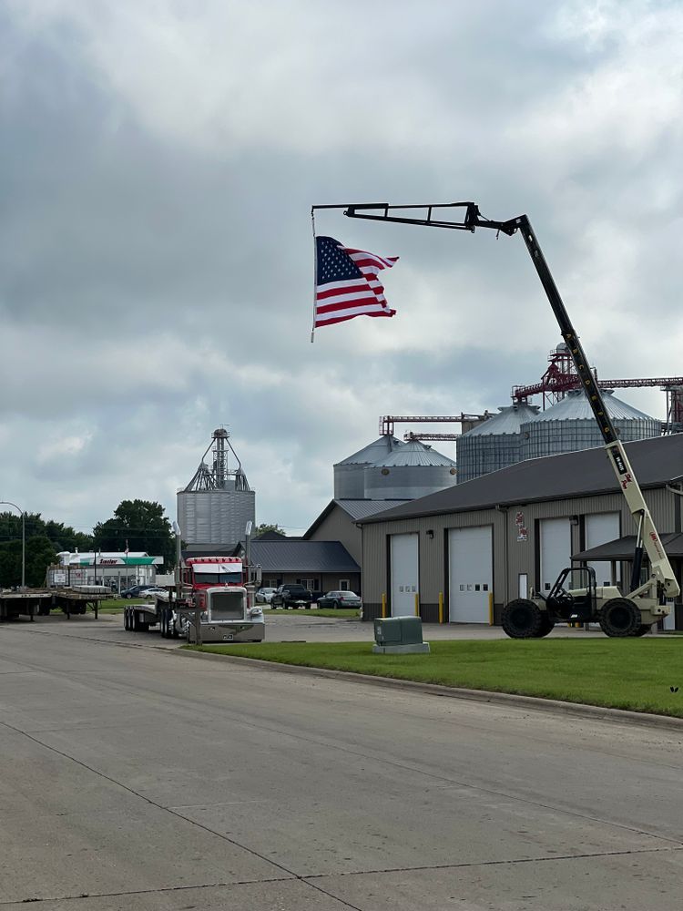 An american flag is hanging from a crane outside of a building