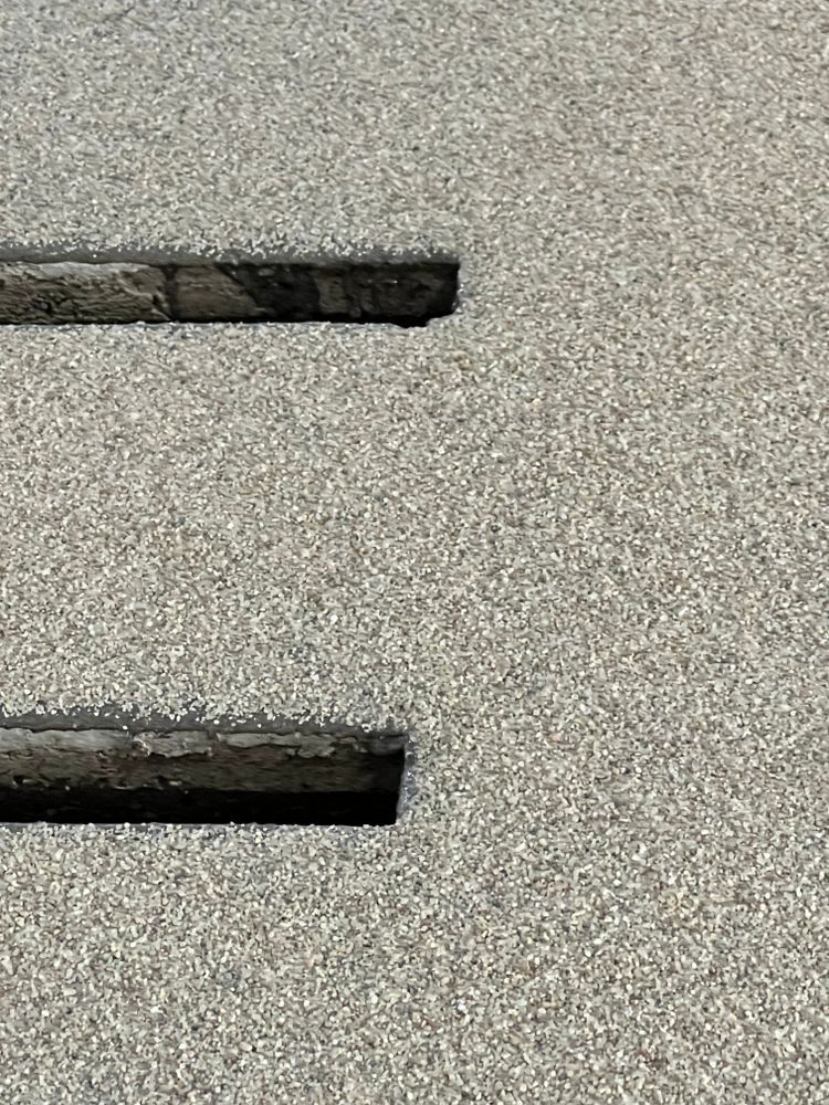 A close up of a gray carpet with a hole in the middle.
