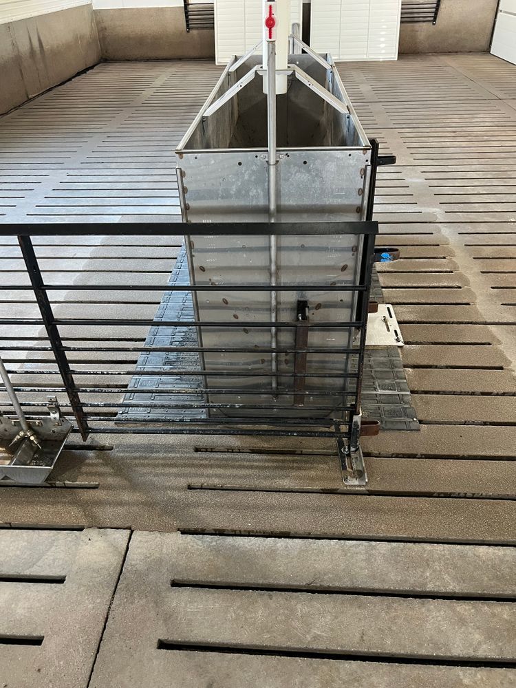 A metal container is sitting on a wooden floor next to a fence.