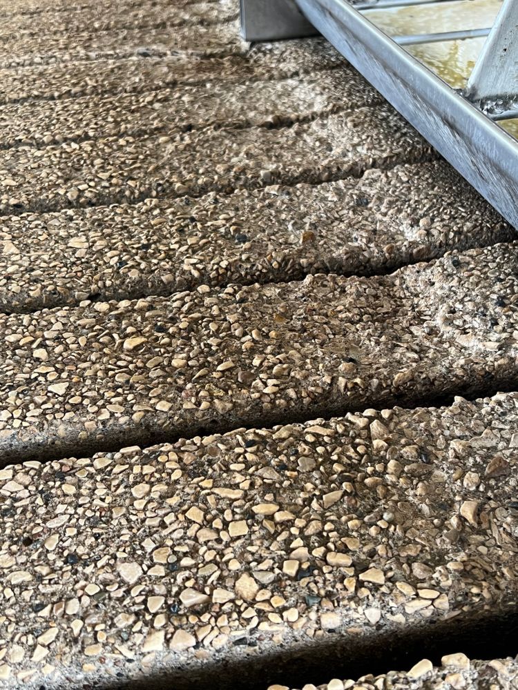 A close up of a concrete floor with a ladder in the background.