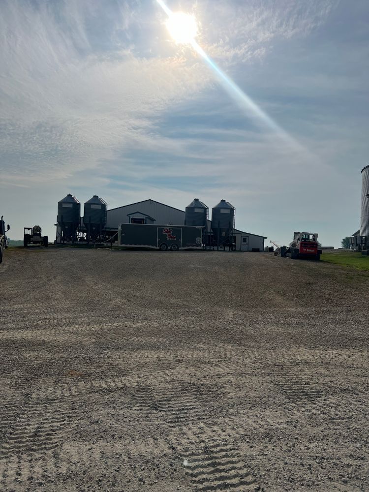 The sun is shining brightly on a dirt road in front of a farm.