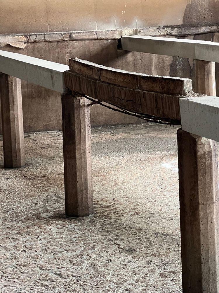 A wooden table is sitting on top of concrete pillars in a room.