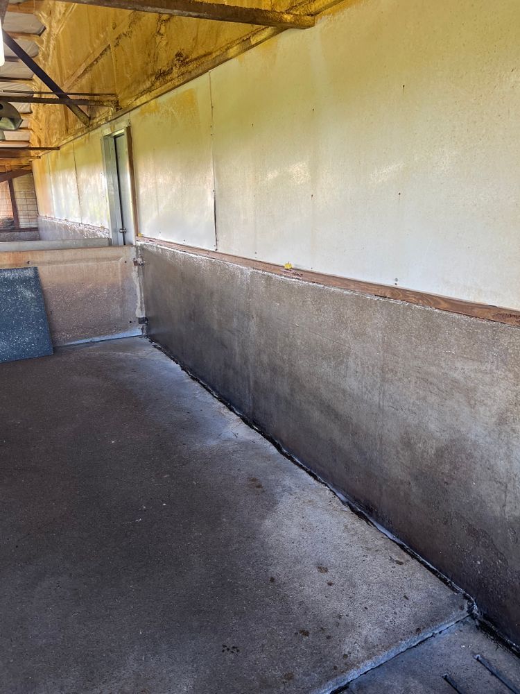 A long hallway with a concrete floor and a white wall