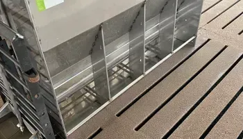 A stainless steel feeder is sitting on top of a wooden floor.