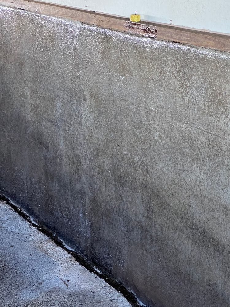 A close up of a concrete wall with a wooden trim.