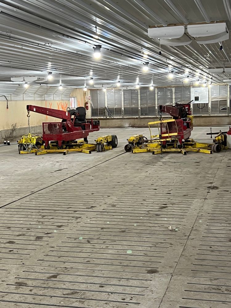 A row of tractors are parked in a large warehouse.