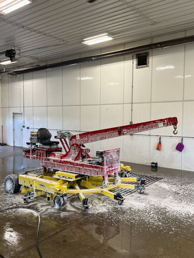 A red and yellow crane is sitting in a car wash.