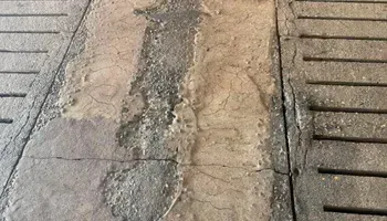 A close up of a concrete floor with a drain on it.
