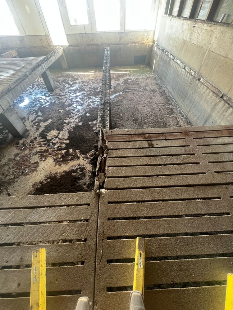 A person is standing on a wooden platform in a dirty room.