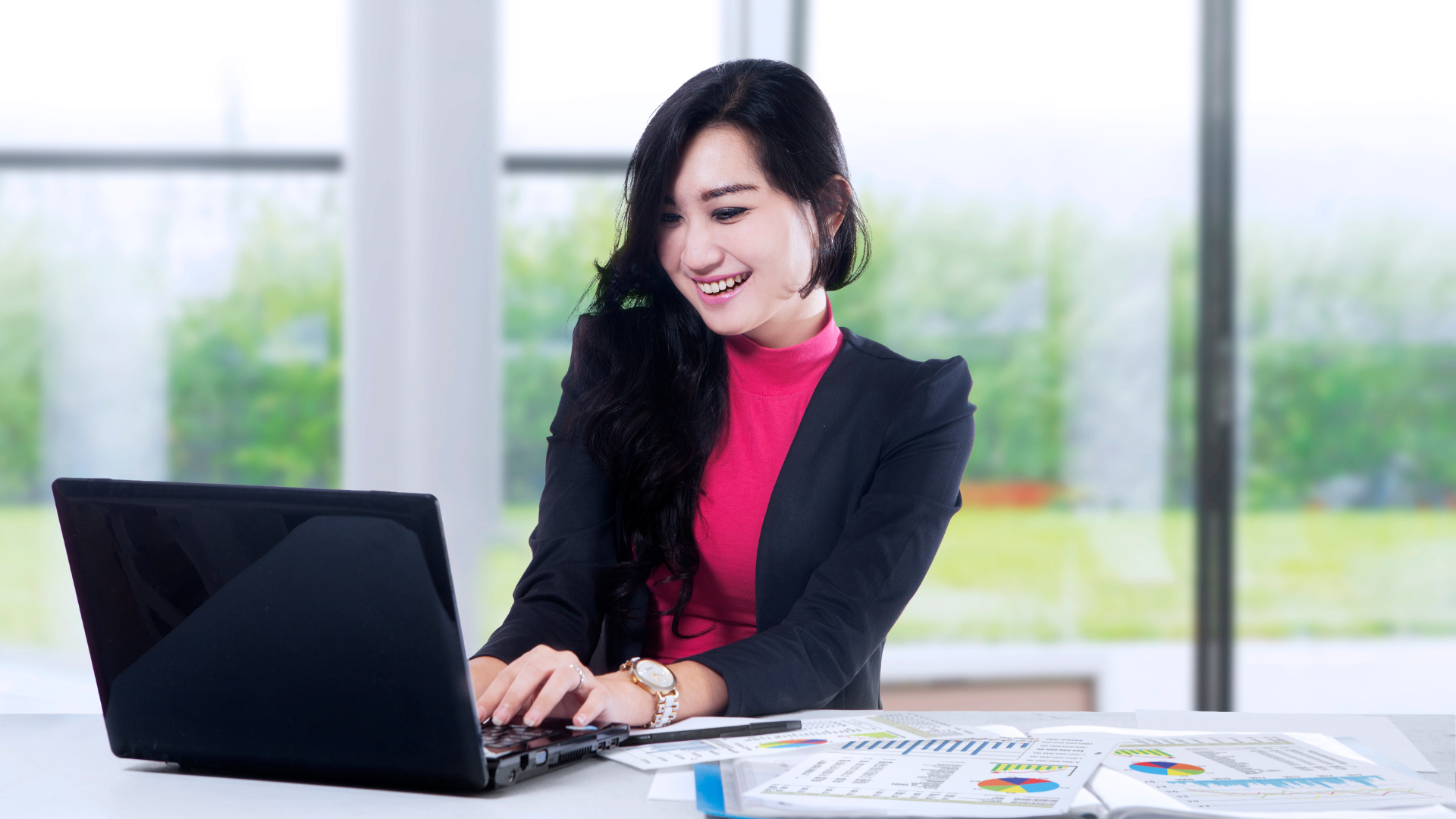 A woman is sitting at a desk using a laptop computer.