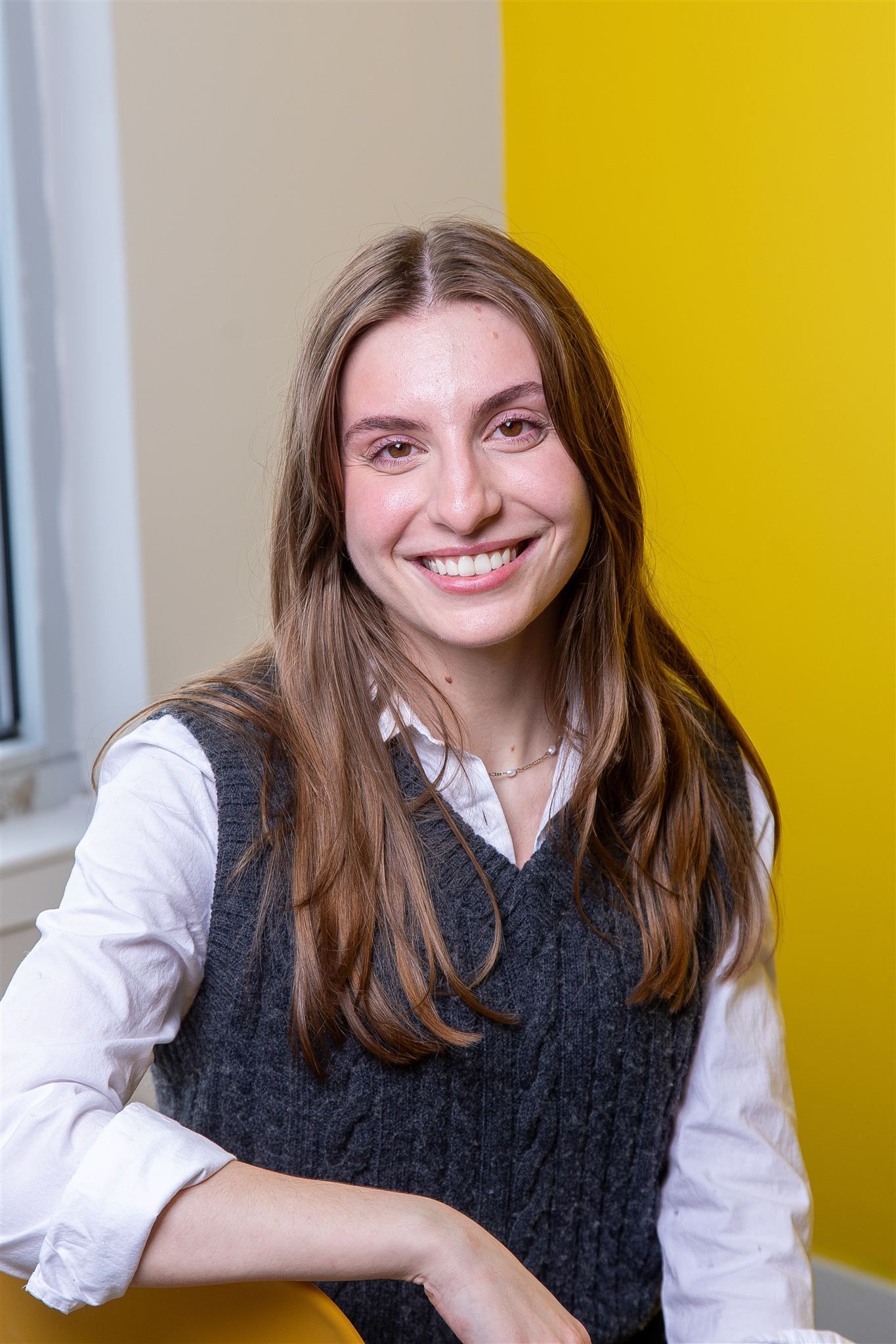 A woman with long blonde hair is standing in front of a window.