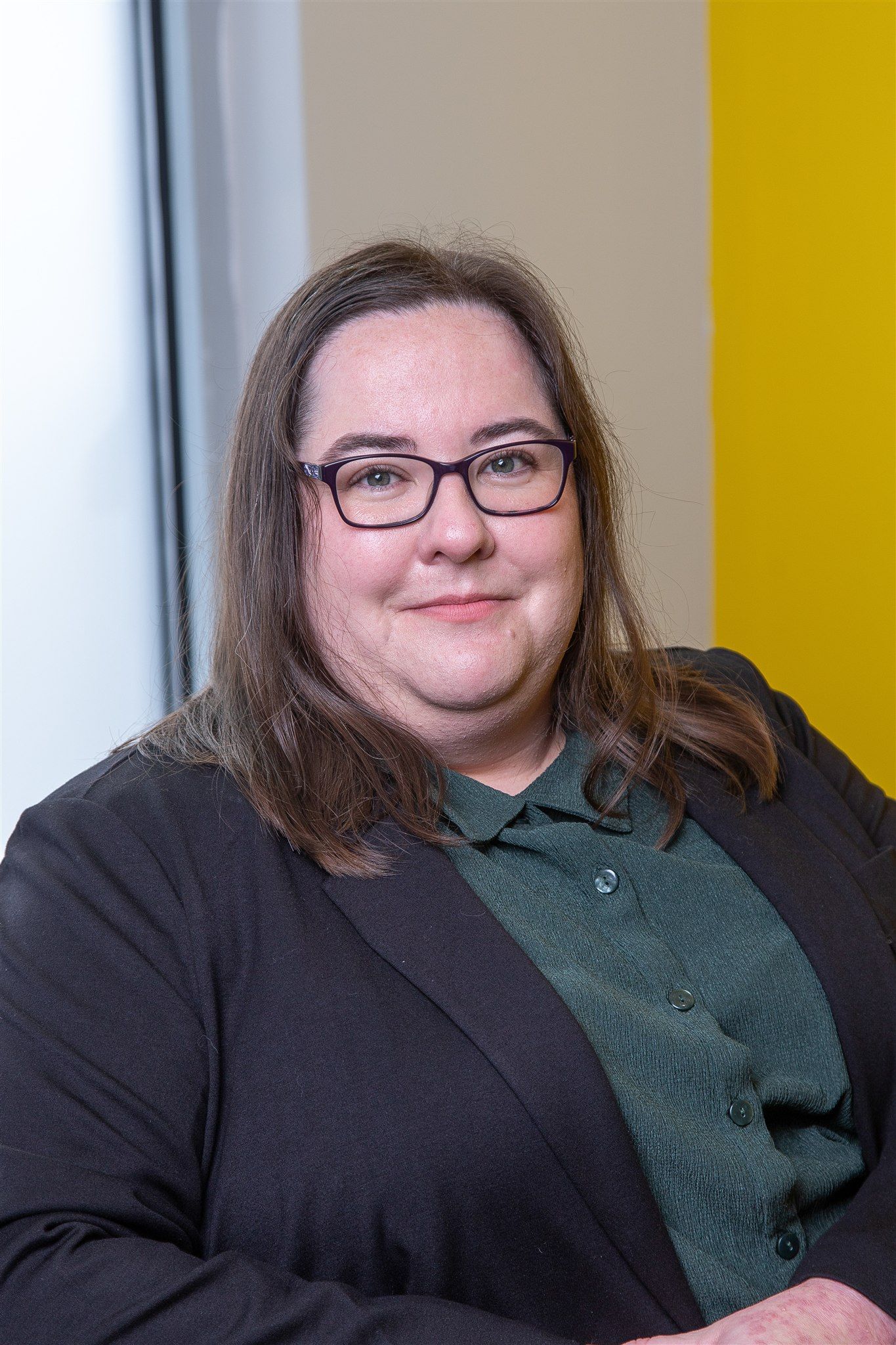 A woman in a black jacket and red shirt is smiling for the camera.
