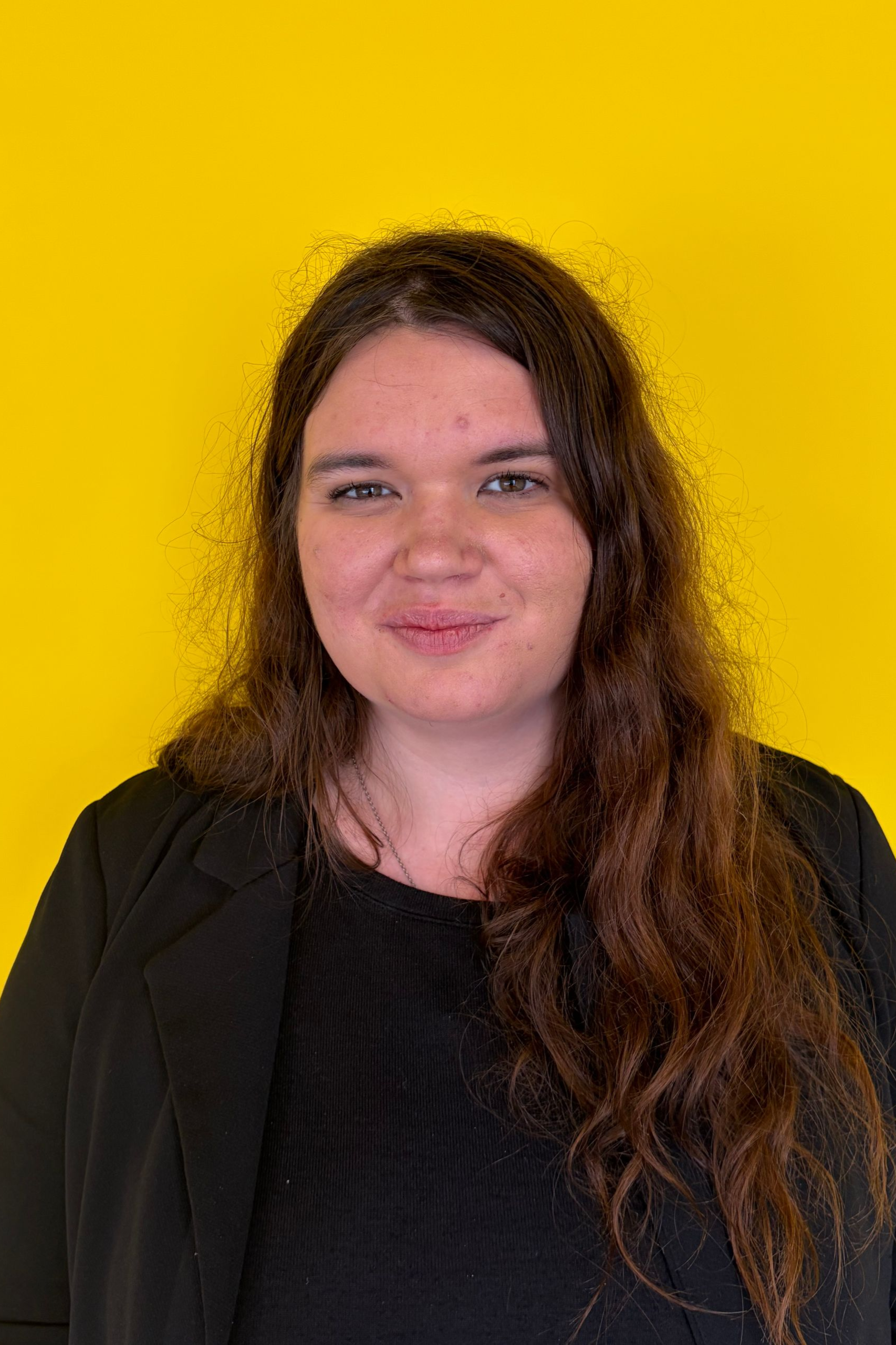 A woman with long blonde hair is standing in front of a window.