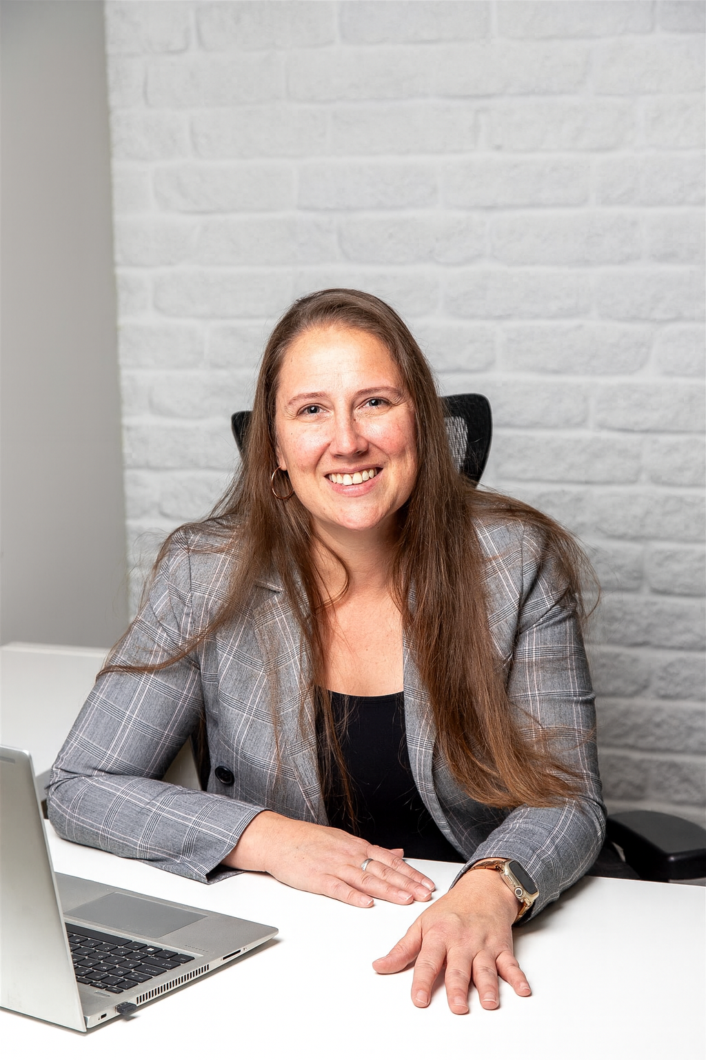 A woman in a black jacket and red shirt is smiling for the camera.