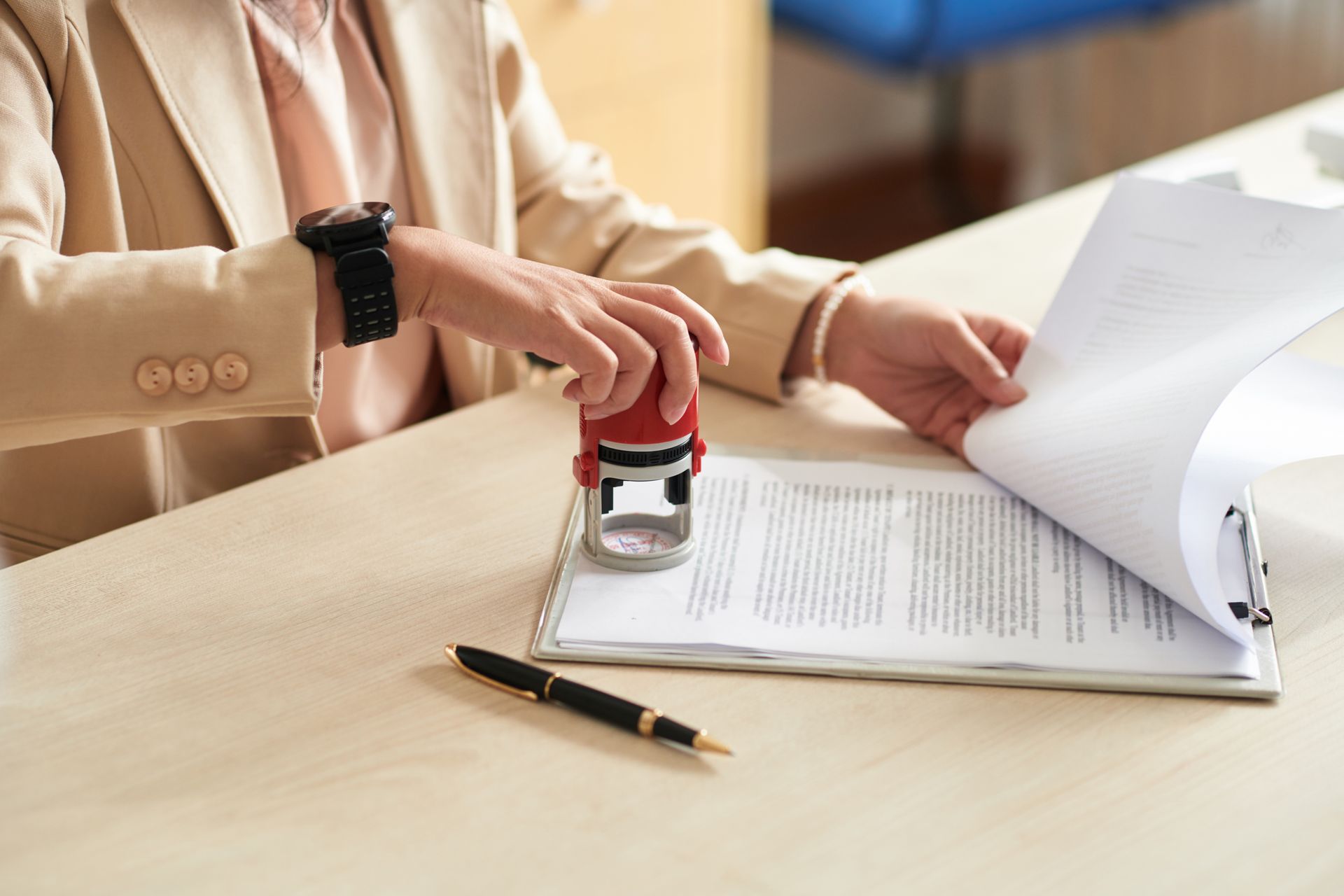 A woman is putting a stamp on a piece of paper.