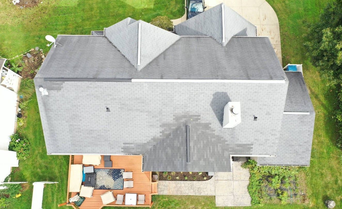 An aerial view of a large house with a gray roof and a wooden deck.