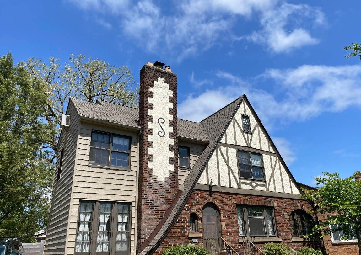 A large brick house with a chimney and a blue sky in the background.