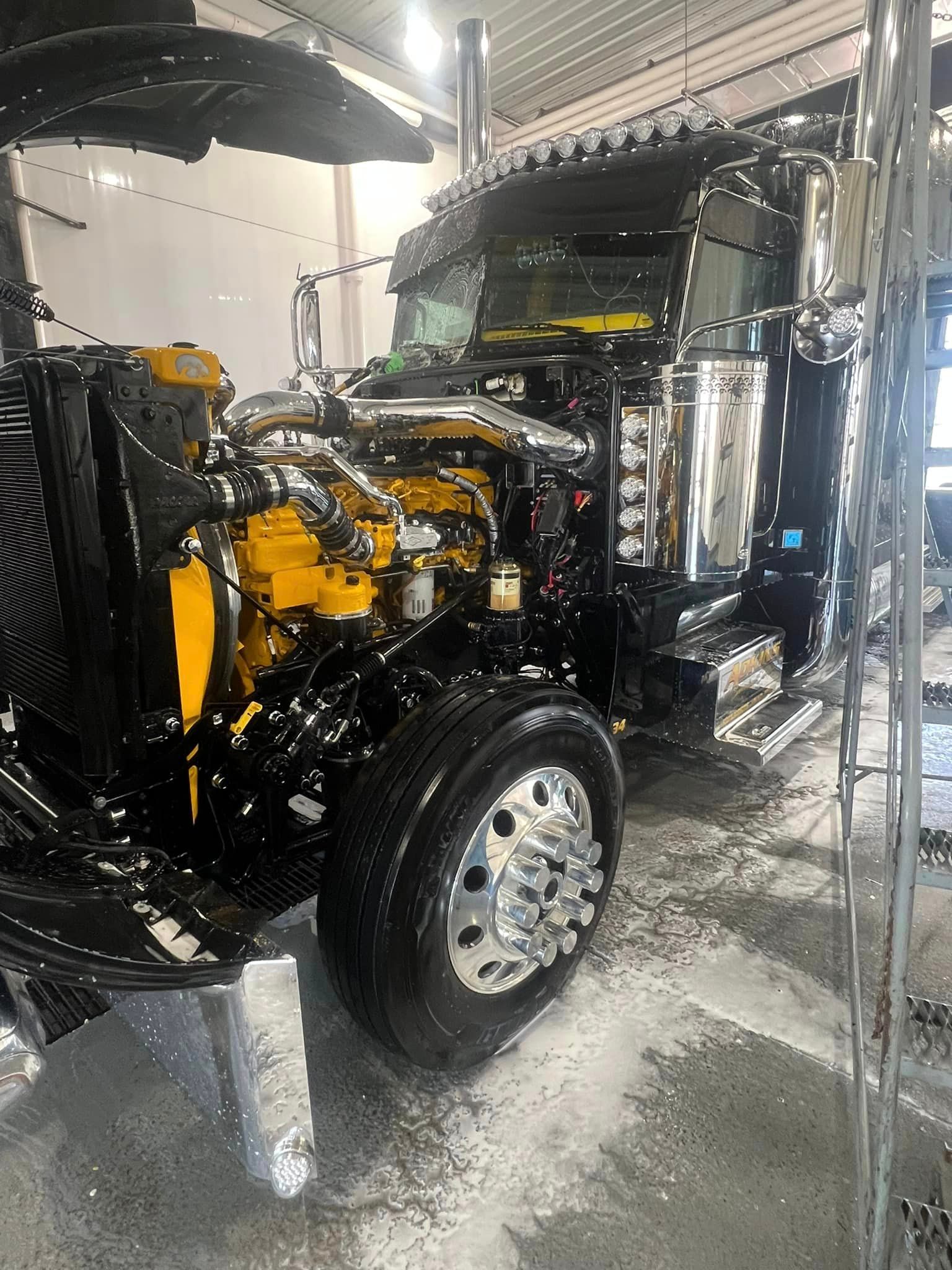 A black and yellow semi truck is parked in a garage.