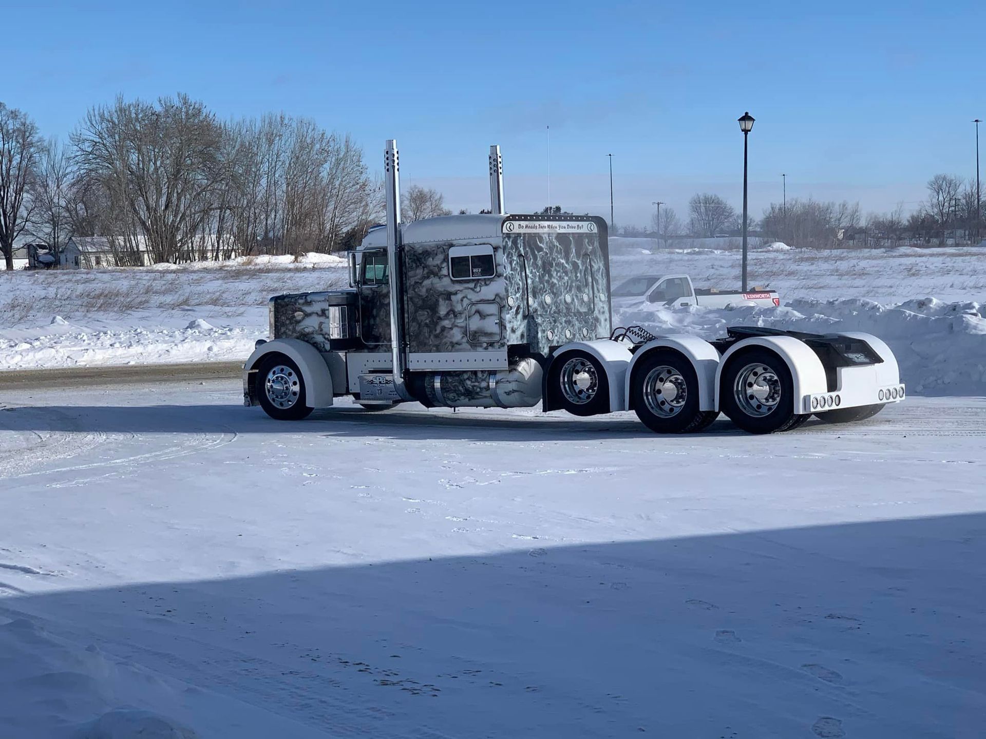 A semi truck is driving down a snowy road.