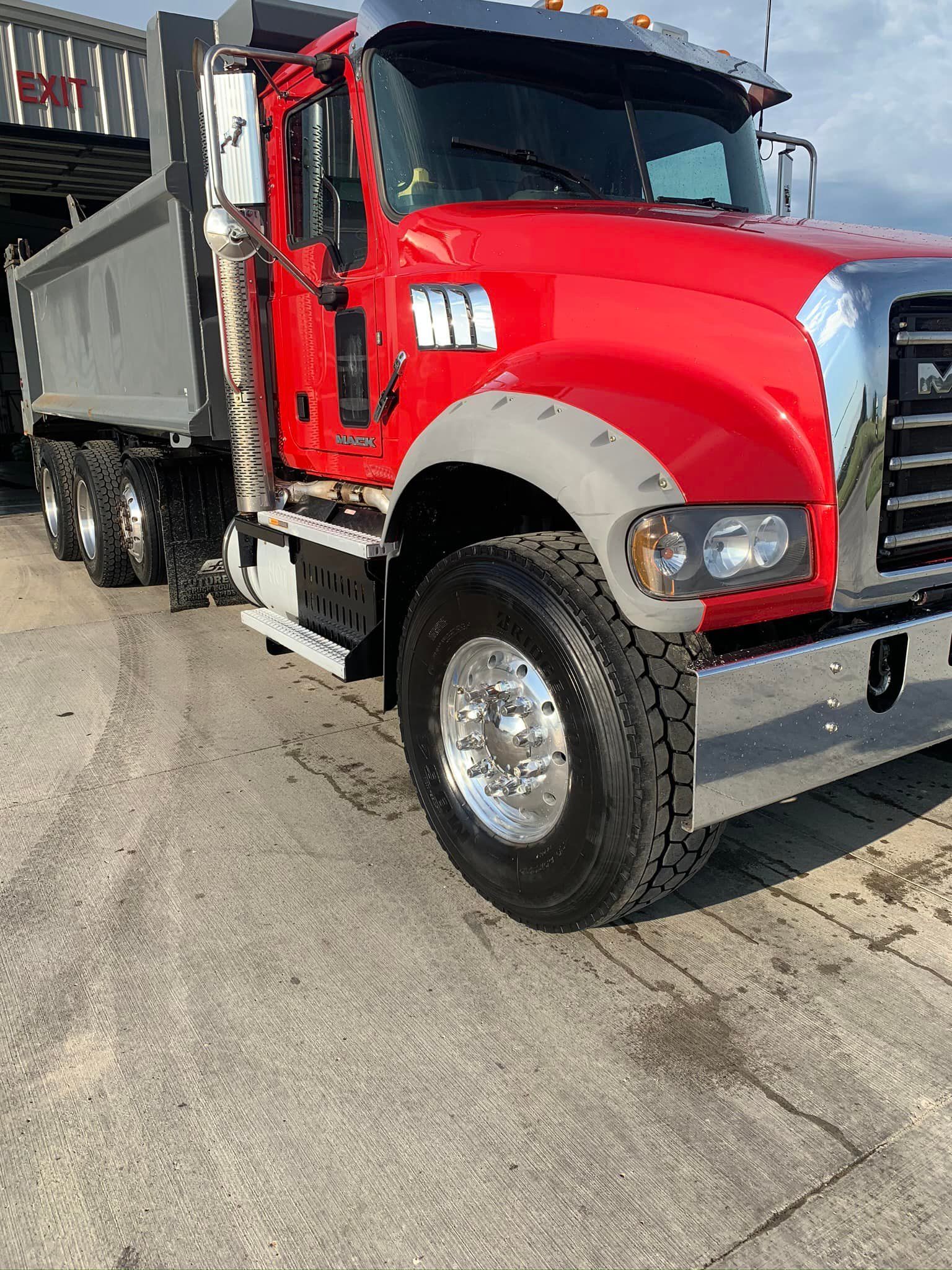 A red dump truck is parked on the side of the road.