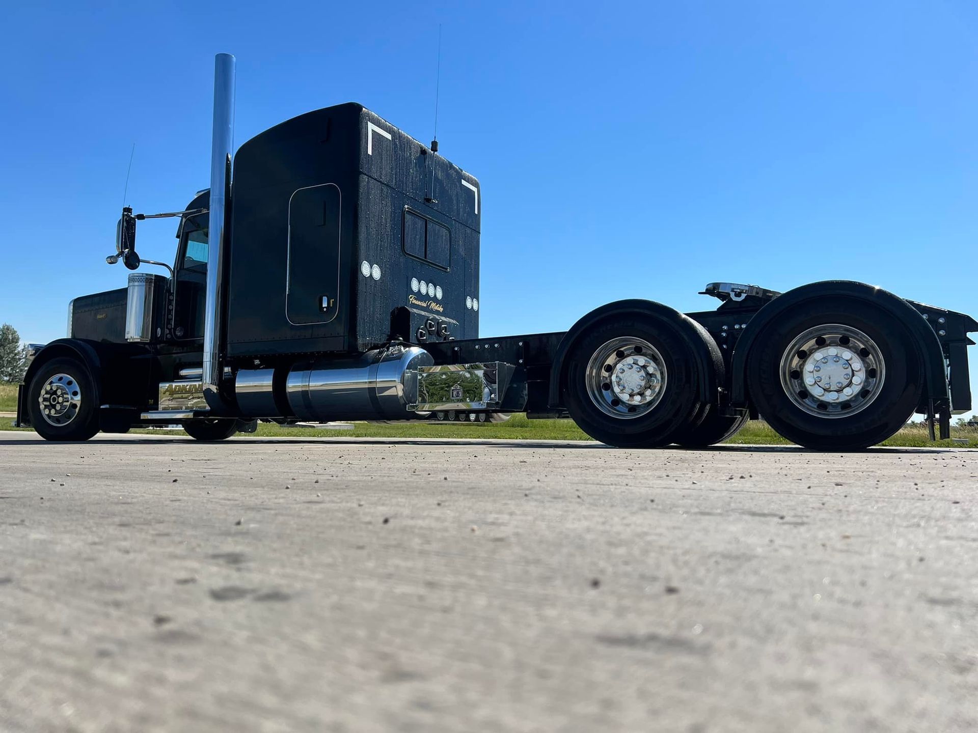 A black semi truck is parked on the side of the road