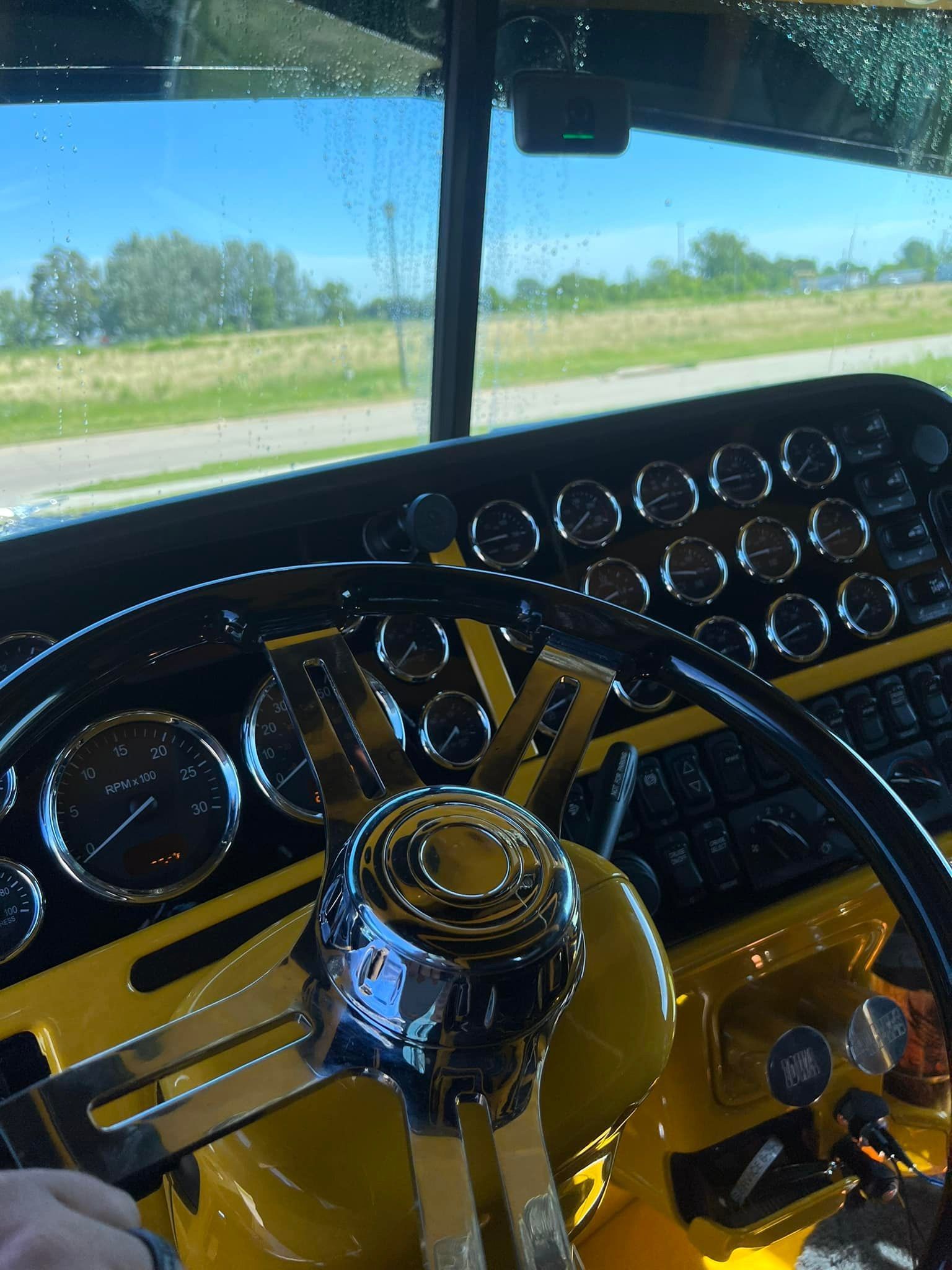 A person is sitting in the driver 's seat of a yellow truck.