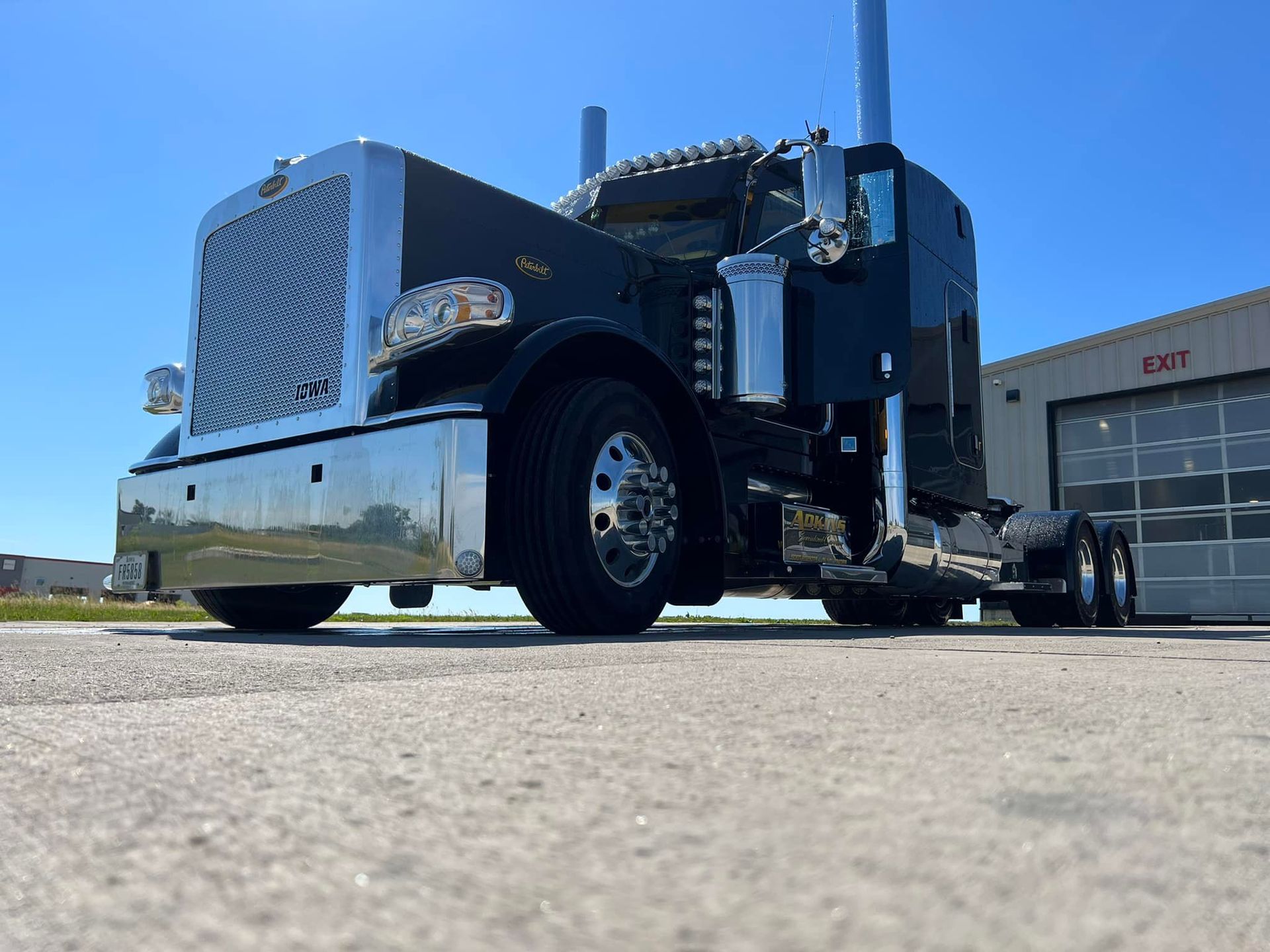 A black semi truck is parked in front of a building.