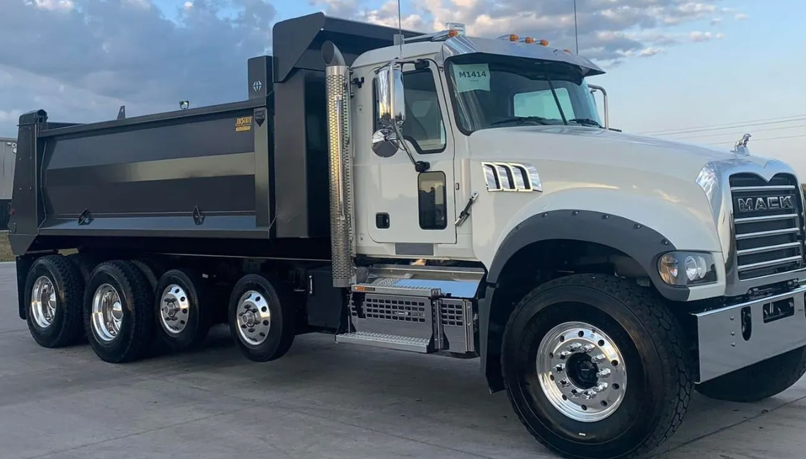A dump truck is parked in a parking lot in front of a building.