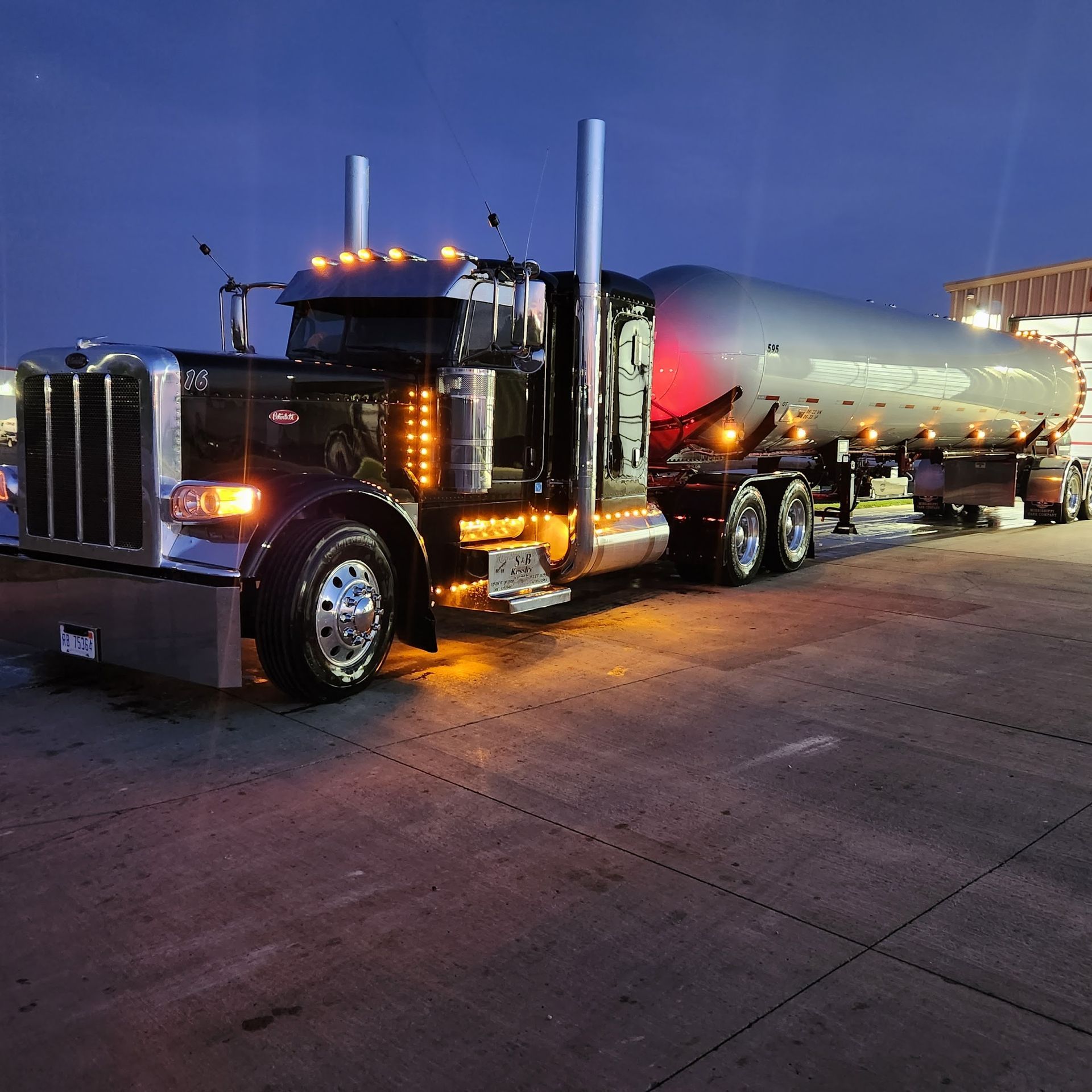 A large semi truck is parked in a parking lot at night