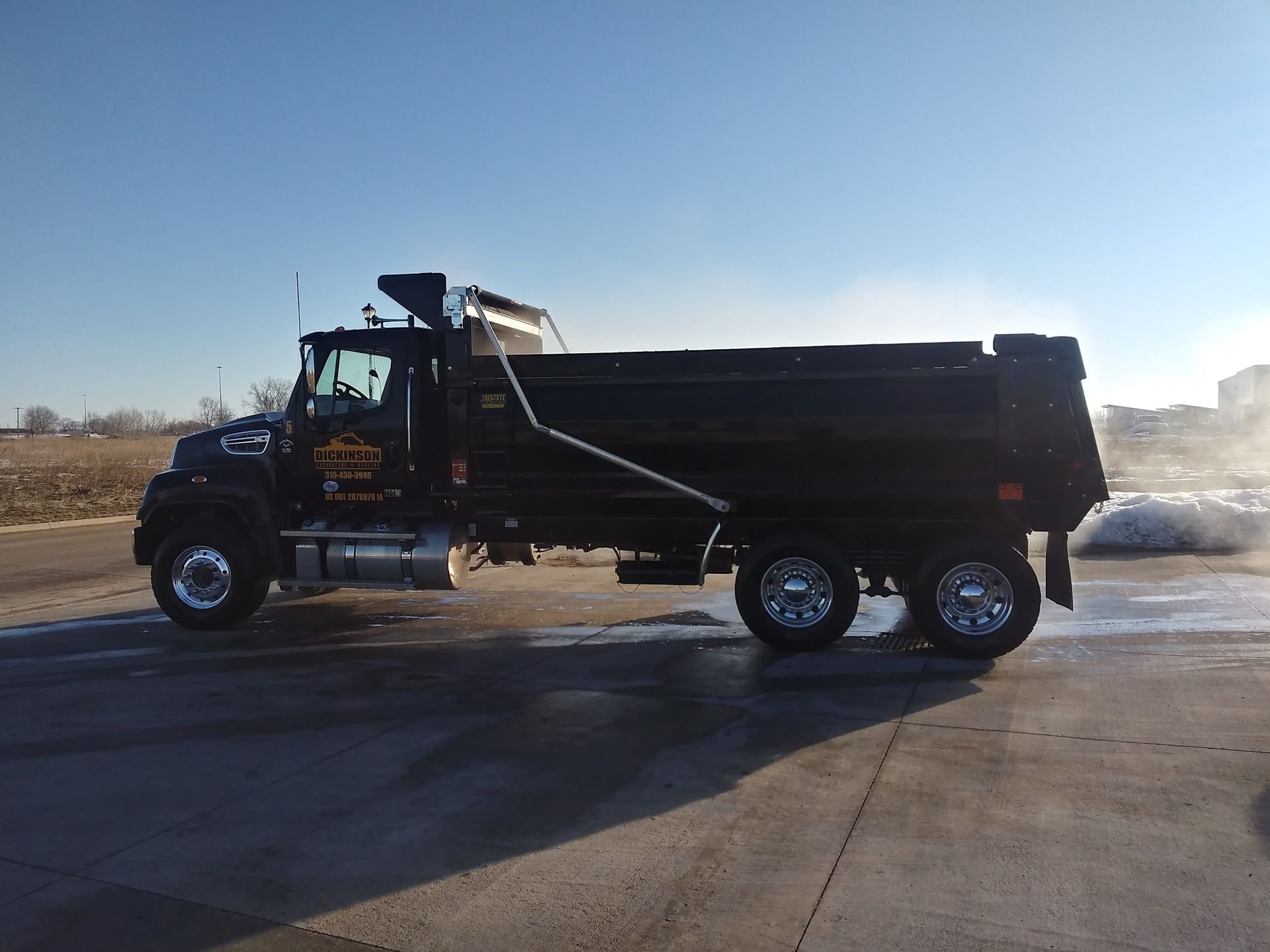 A black dump truck is parked in a parking lot