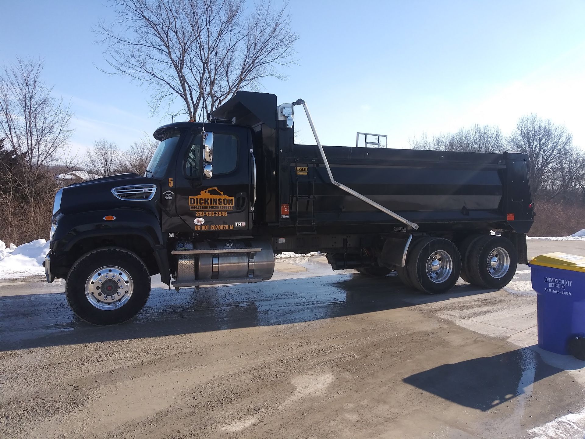 A black dump truck is parked on the side of the road