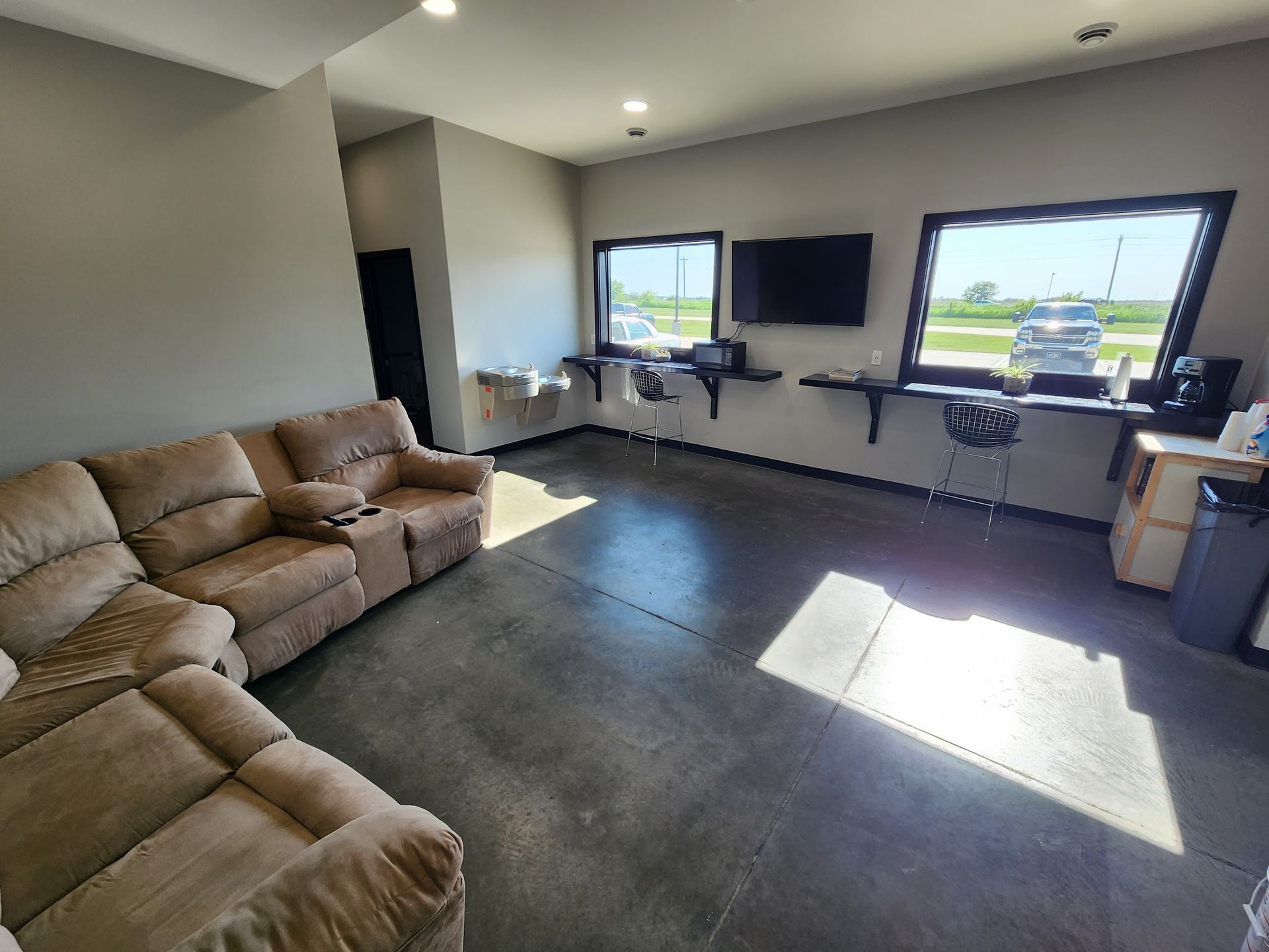 A living room with a couch , television , and two windows.