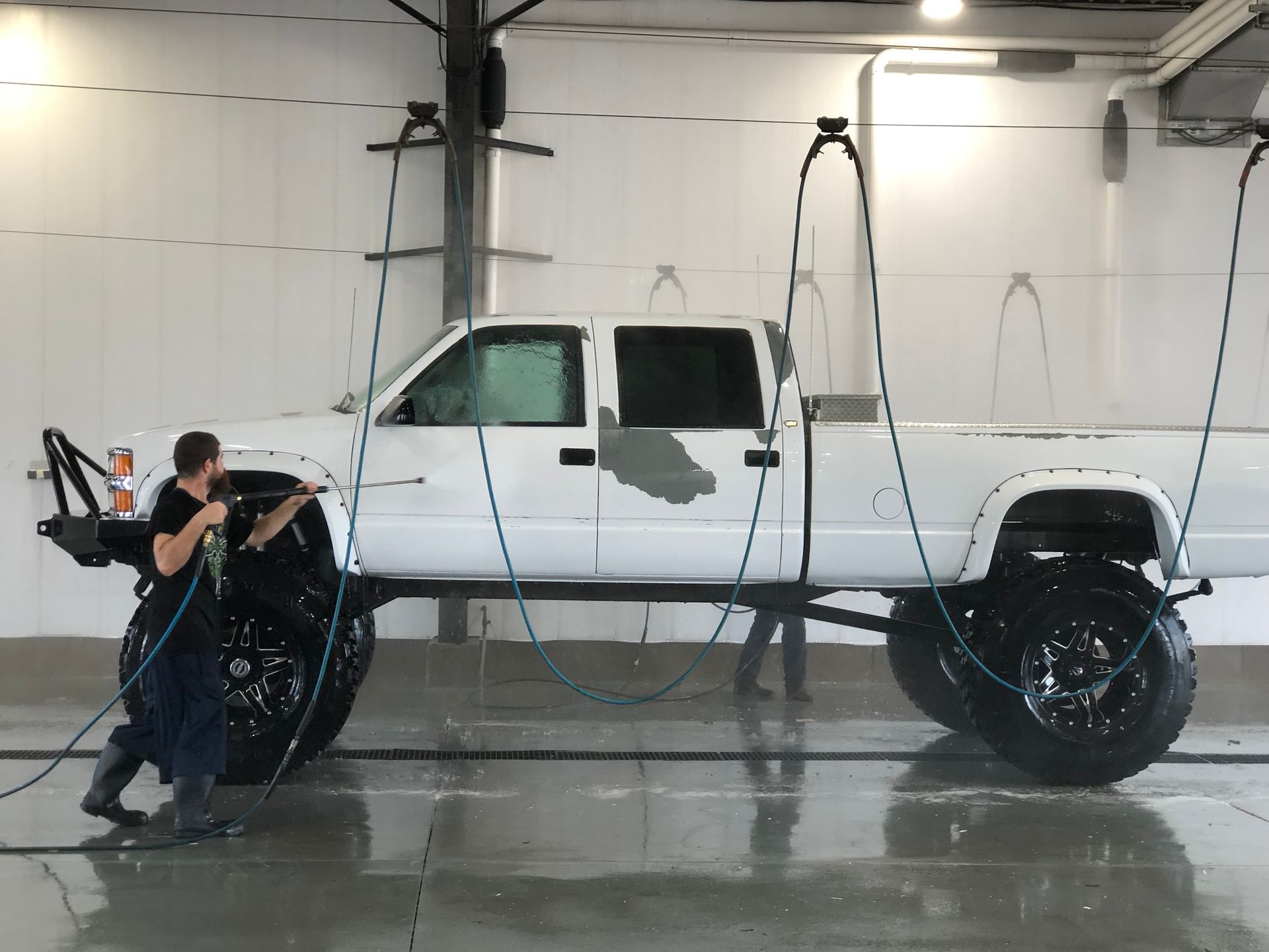 A man is washing a white truck in a garage